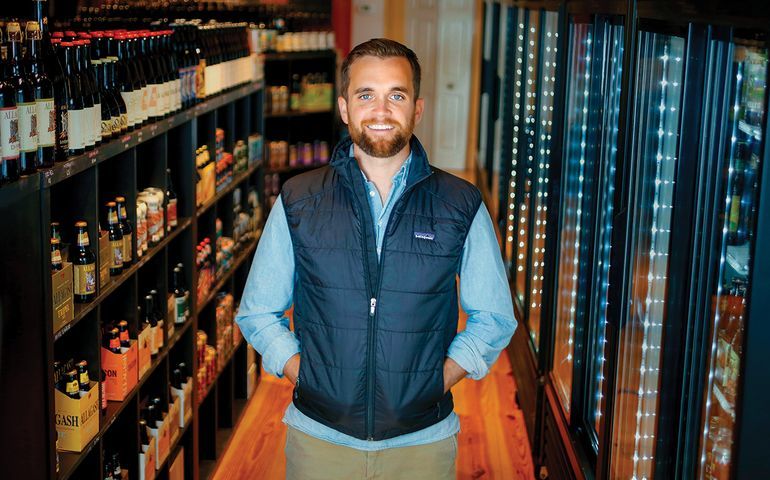 man in front of shelves of wine and  beer