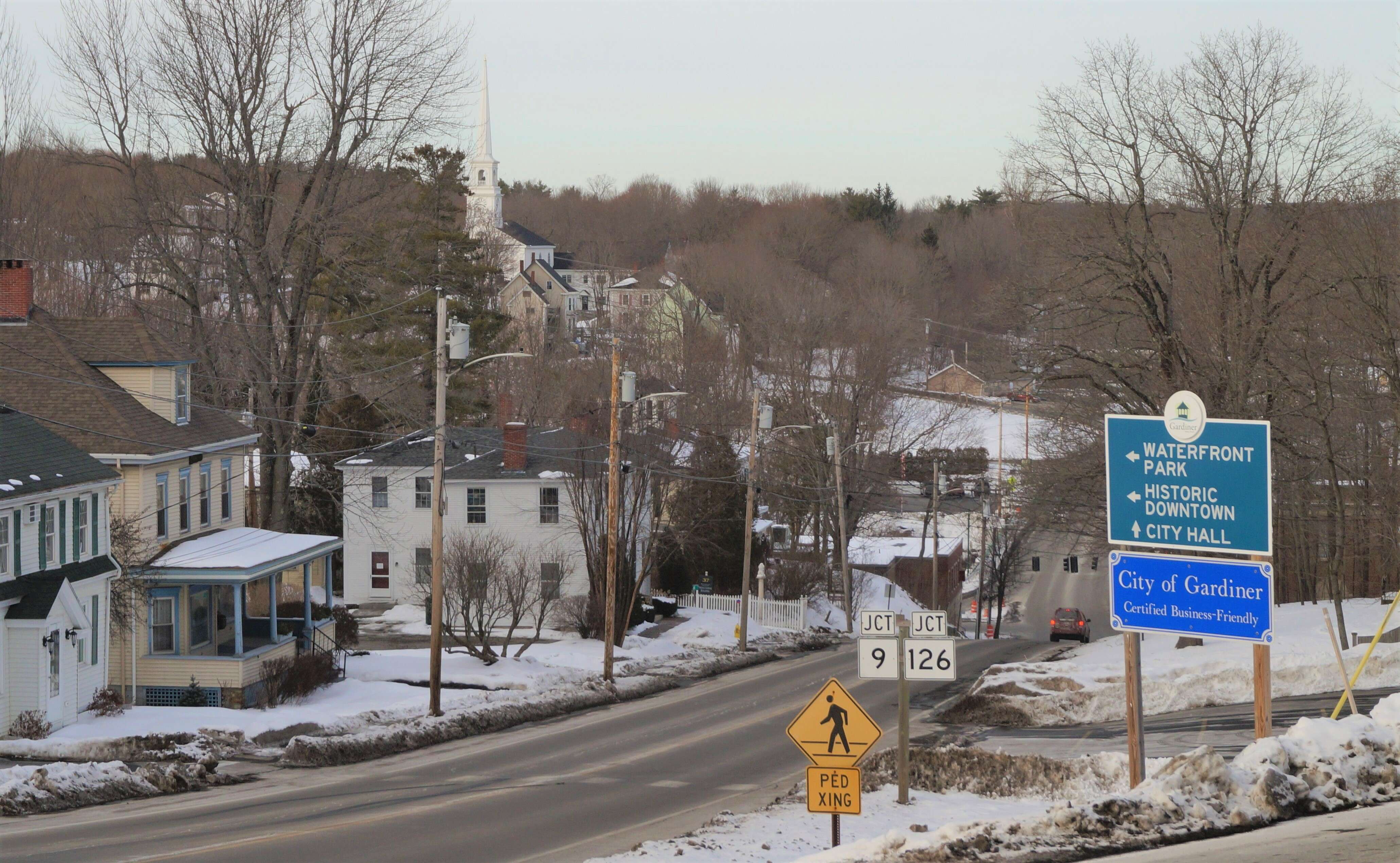 a road going down a snowy hill with a sign that says city of gardiner