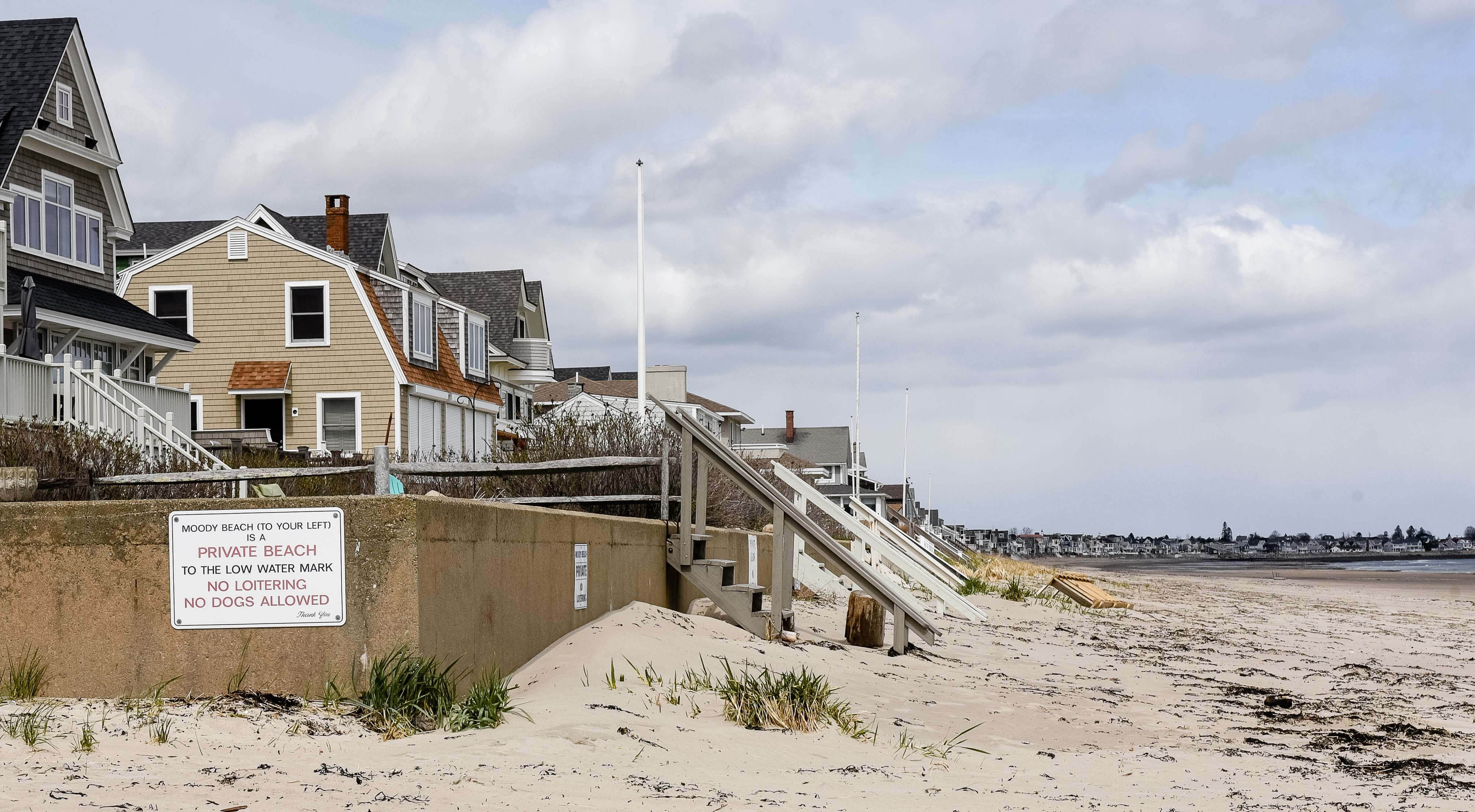 a sign says moody bach to your left is a private beach to the low water mark no loitering no dogs allowed houses stretch along the beach