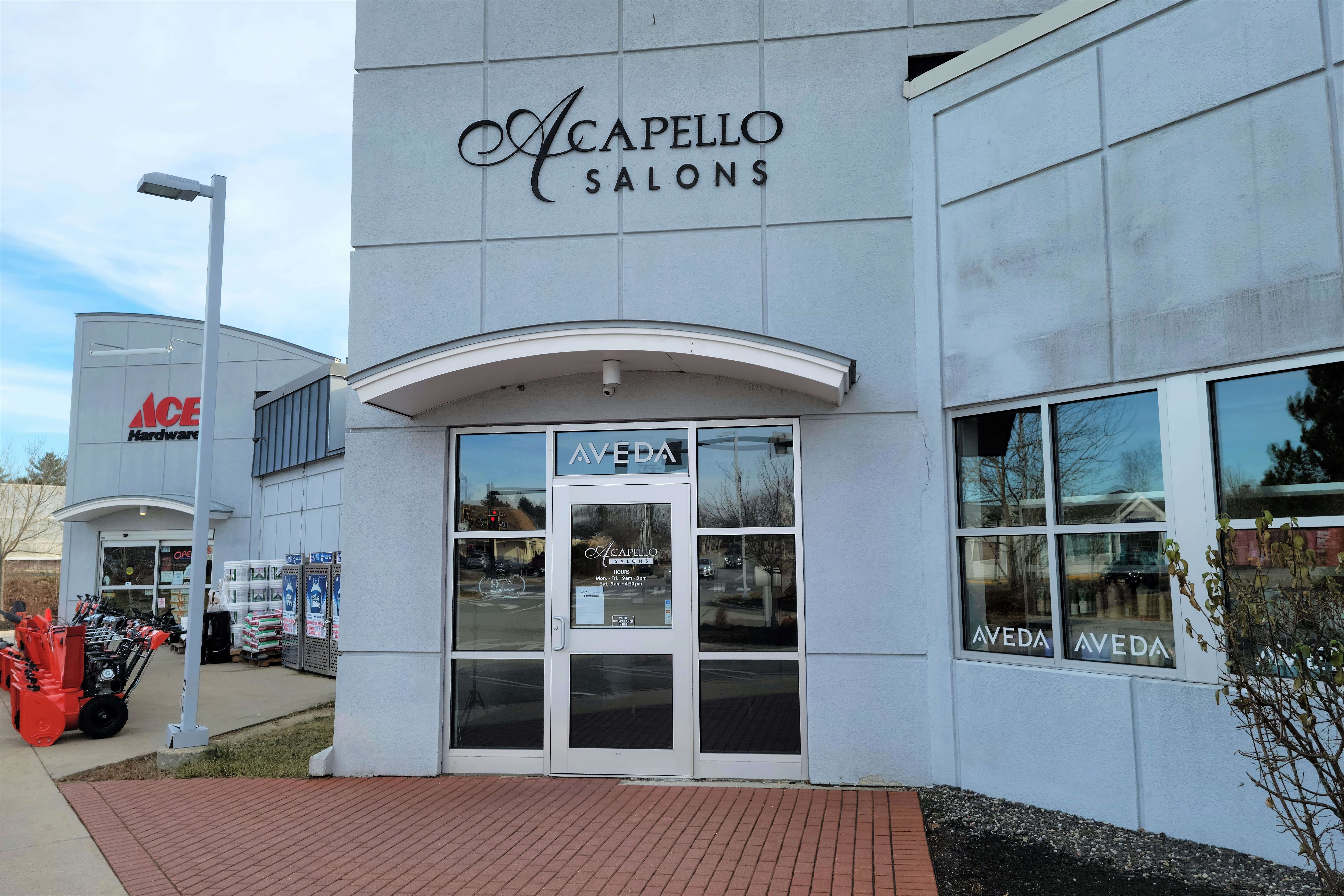 exterior of modern, gray concrete building with "Acapello Salons" sign