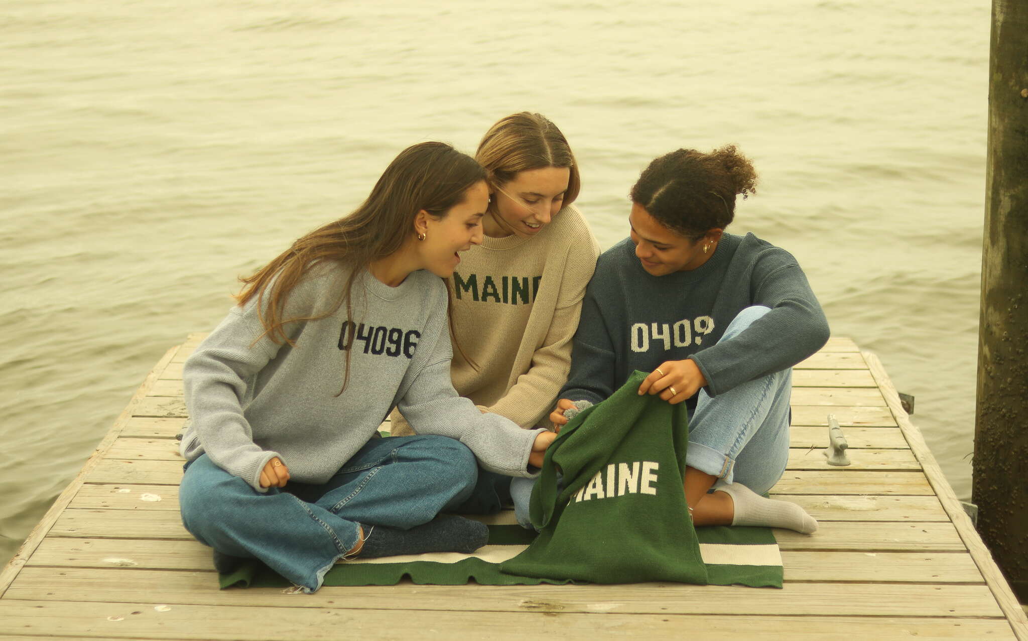 3 people on dock wearing sweatshirts