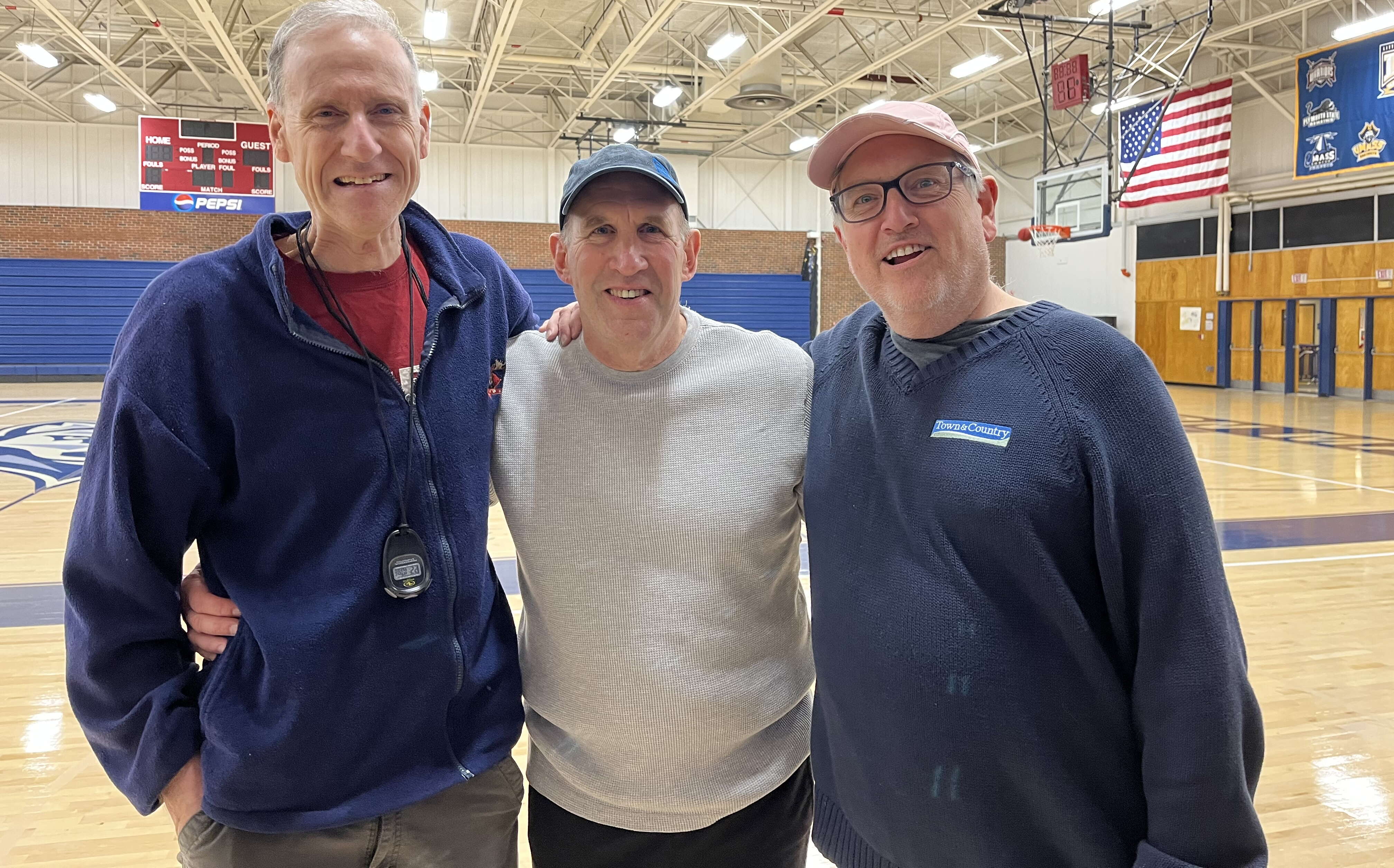 Three men in a gymnasium. 