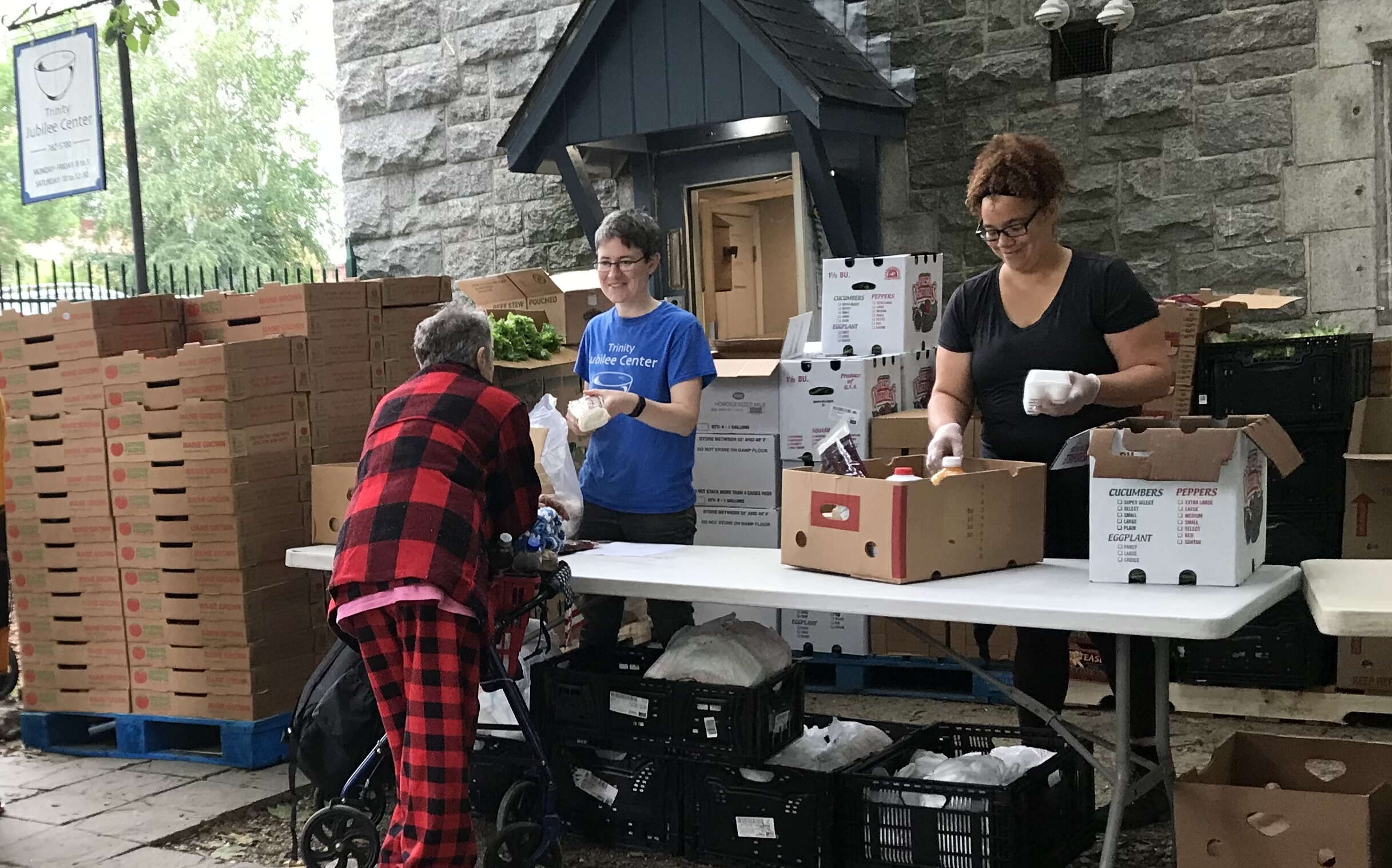 People with Trinity Jubilee Center distribute food to clients outside.