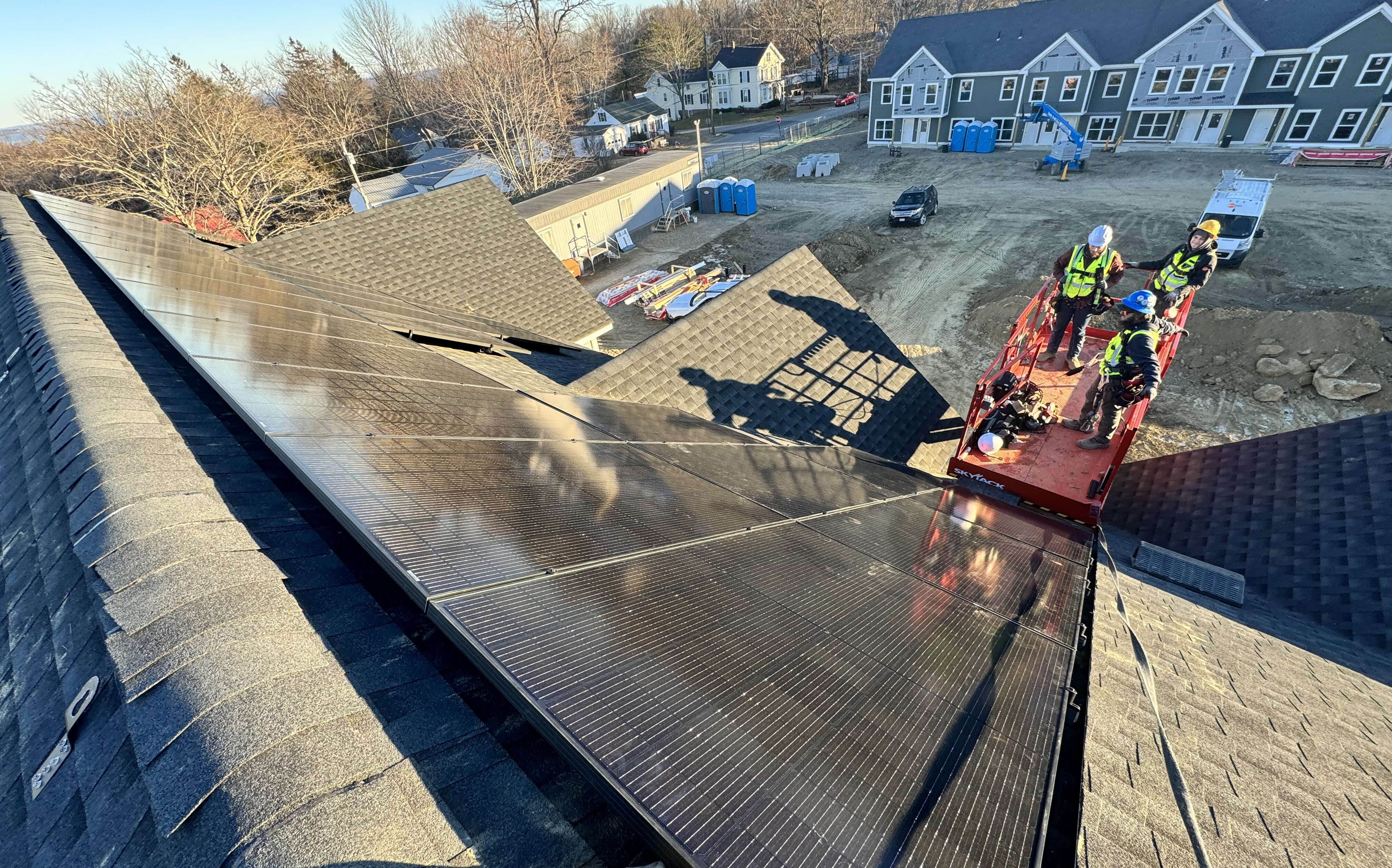 SolarLogix workers are working on solar panels on a roof using a scissorlift