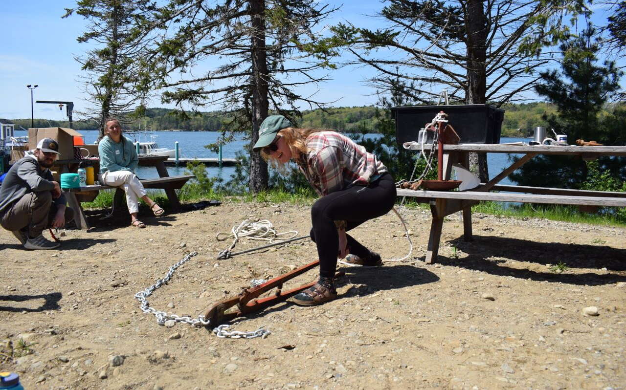 A student in the aquaculture boot camp cuts a chain while others look on.