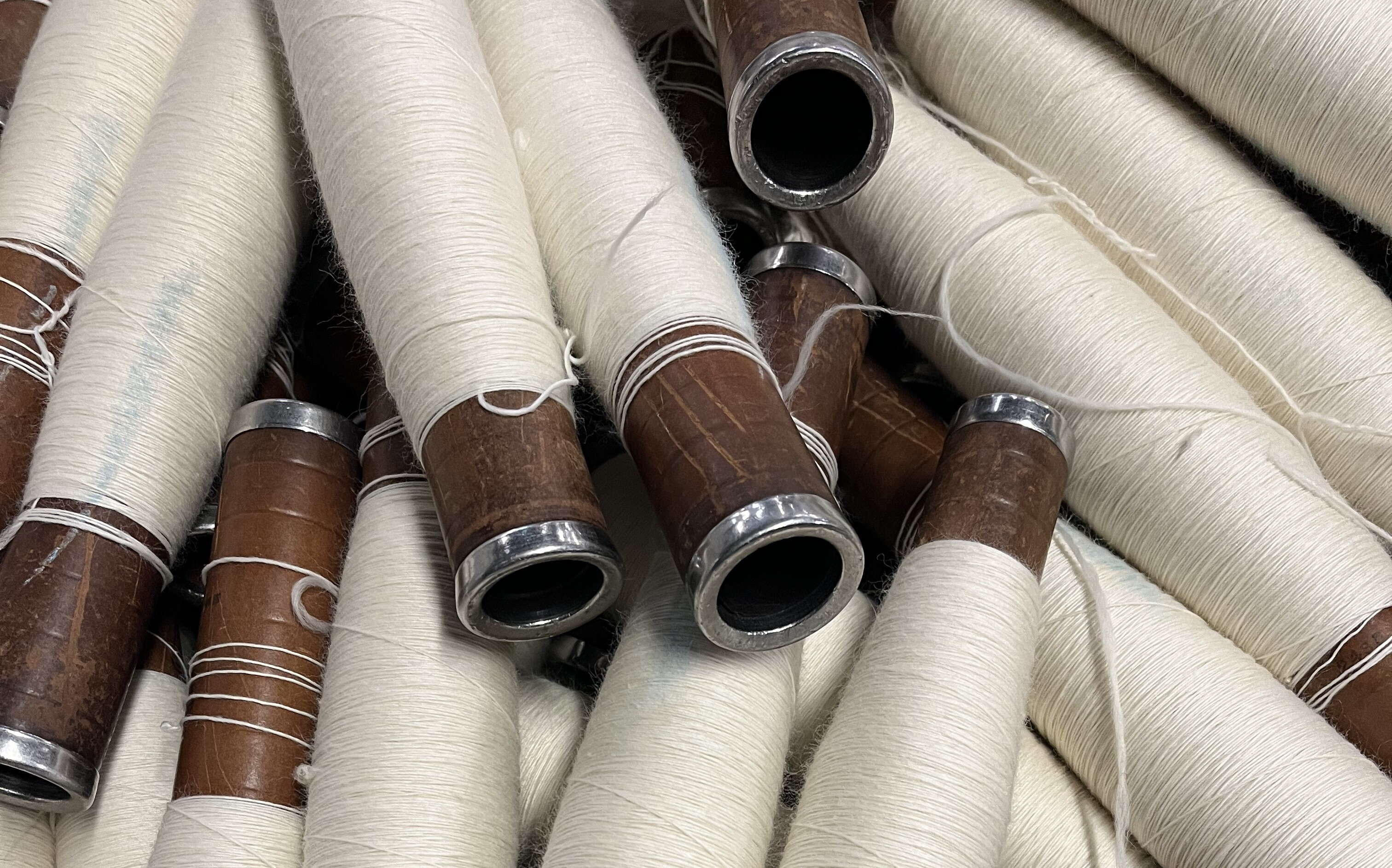 A bin is full of spindles wrapped in white yarn.