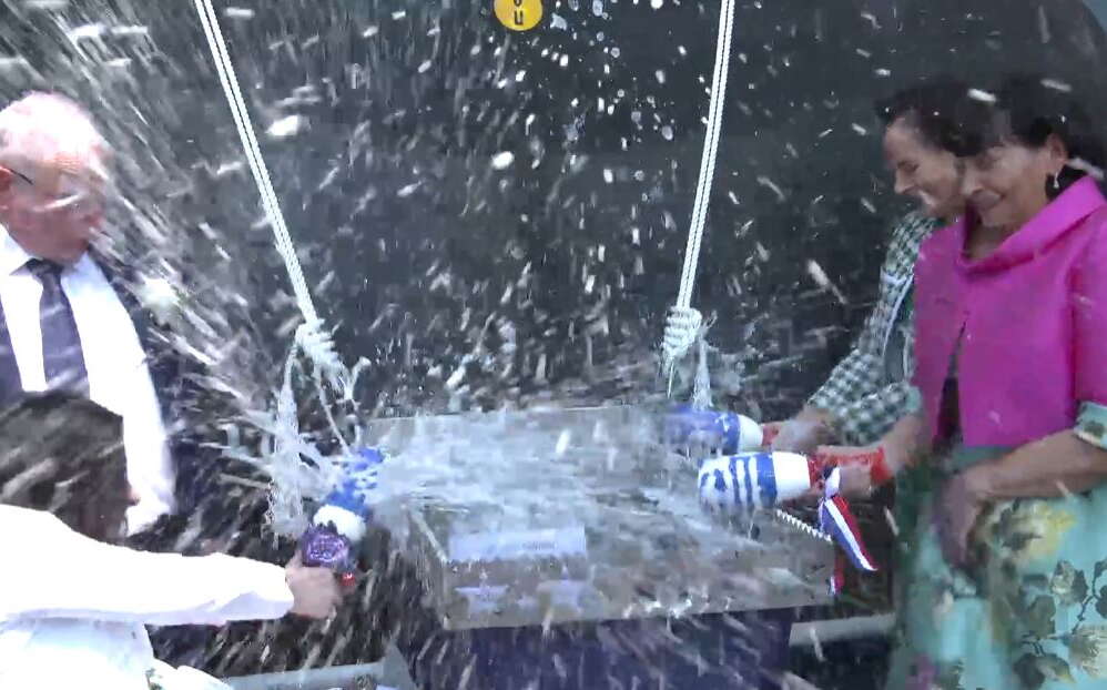 People break bottles on a ship at BIW's ship christening.