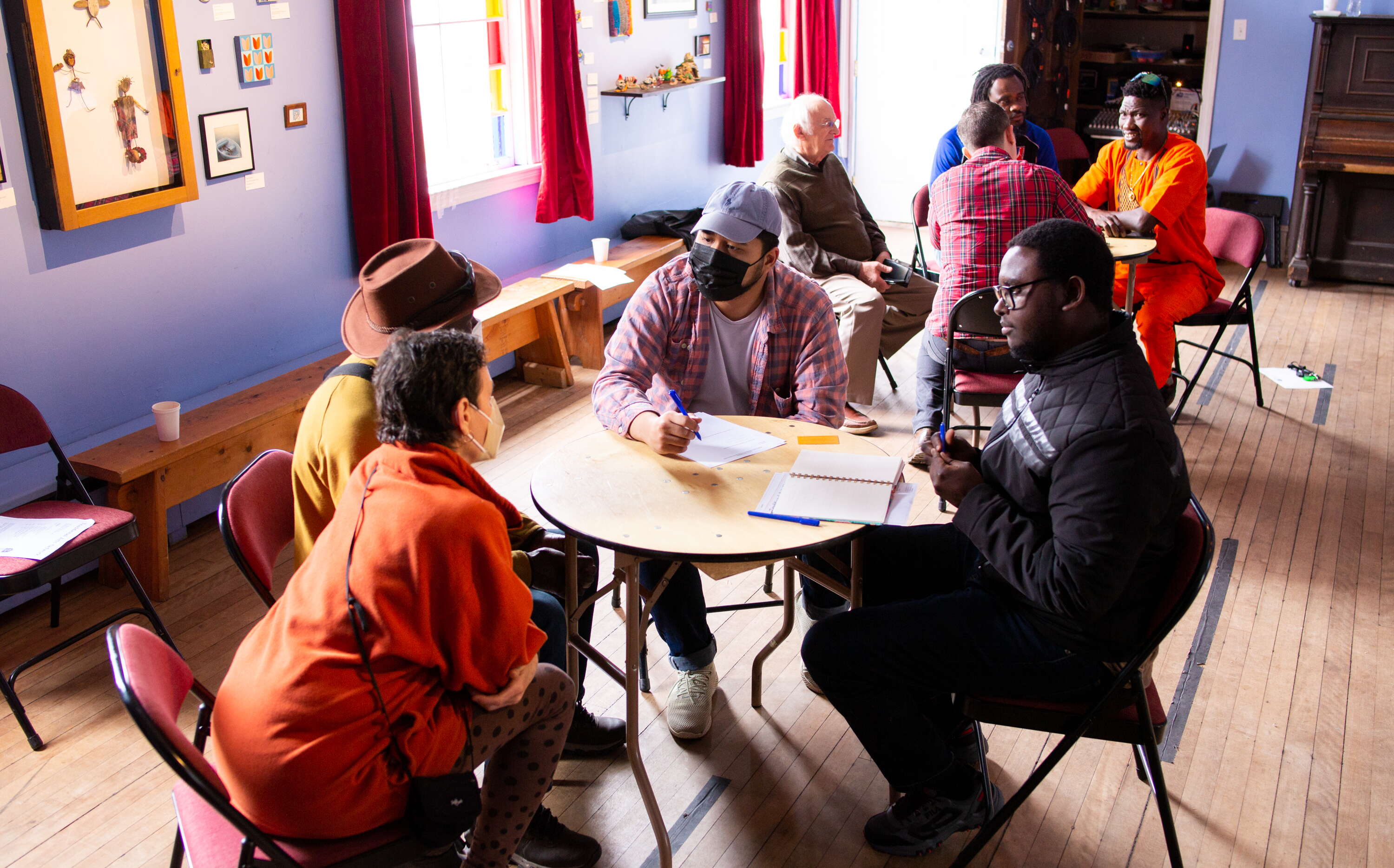 A group of people talk at tables at Mayo Street Arts.