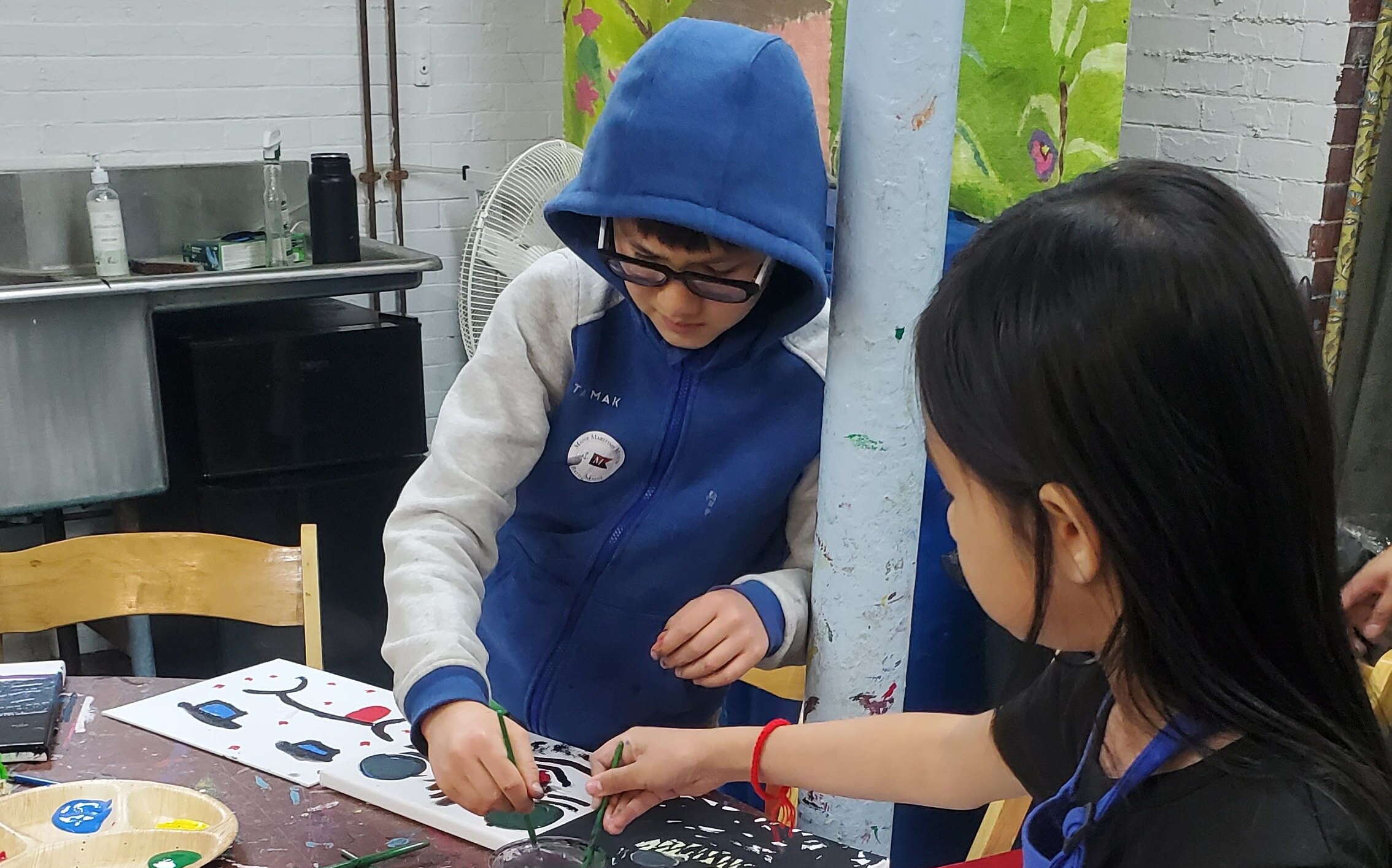 Children paint at a table at Mayo Street Arts.