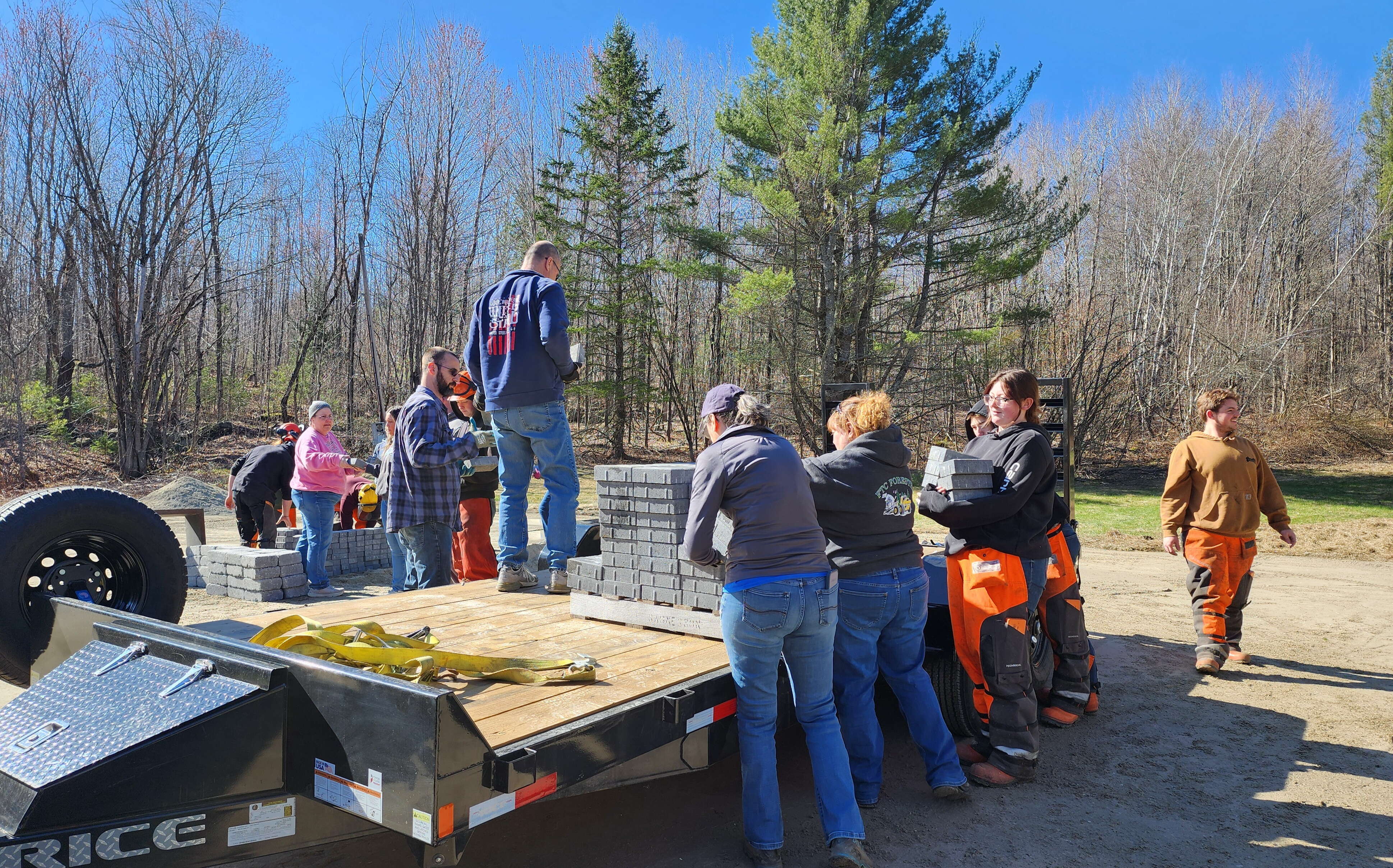 A group of people unload materials from a flatbed.