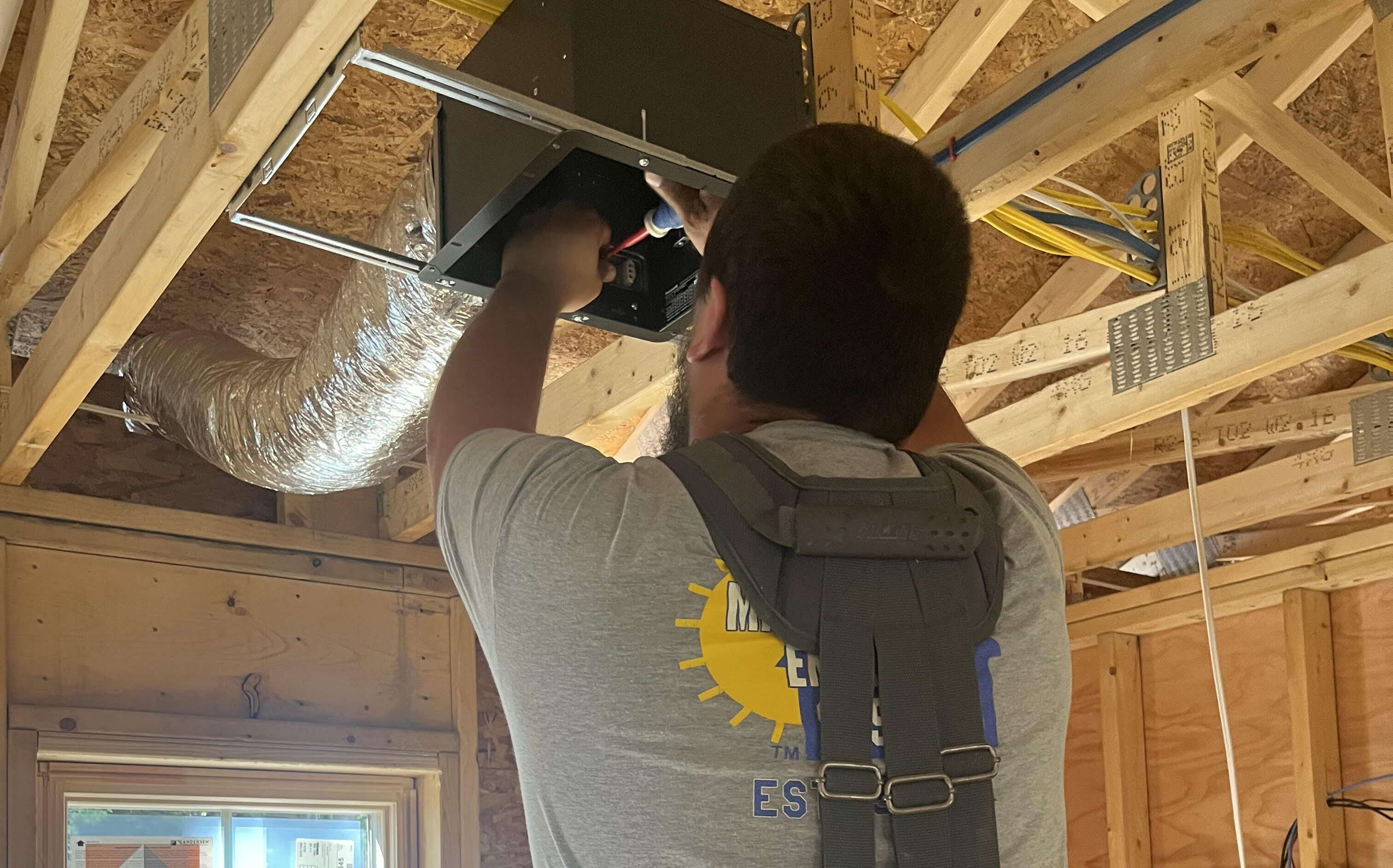 A worker installs wires in the ceiling. 