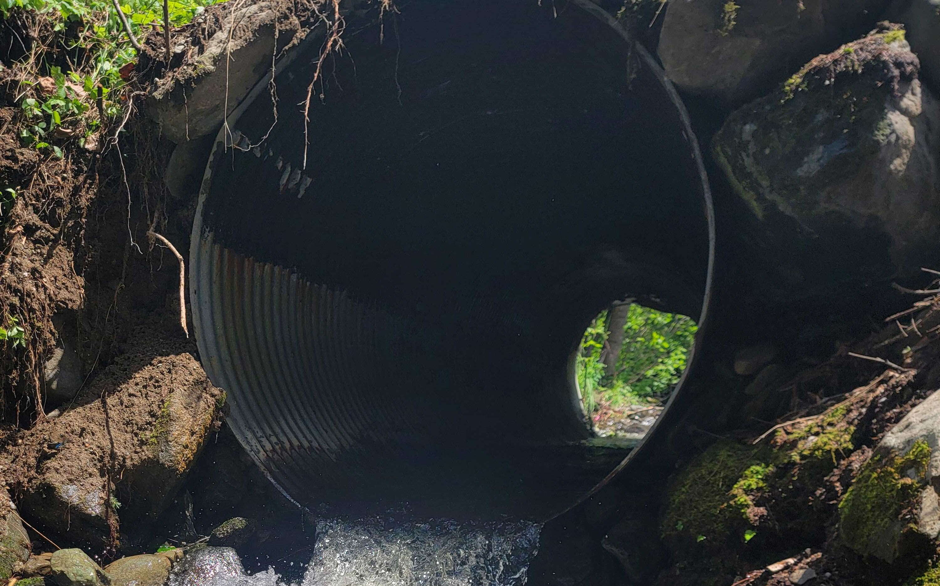 A culvert has water flowing through it.