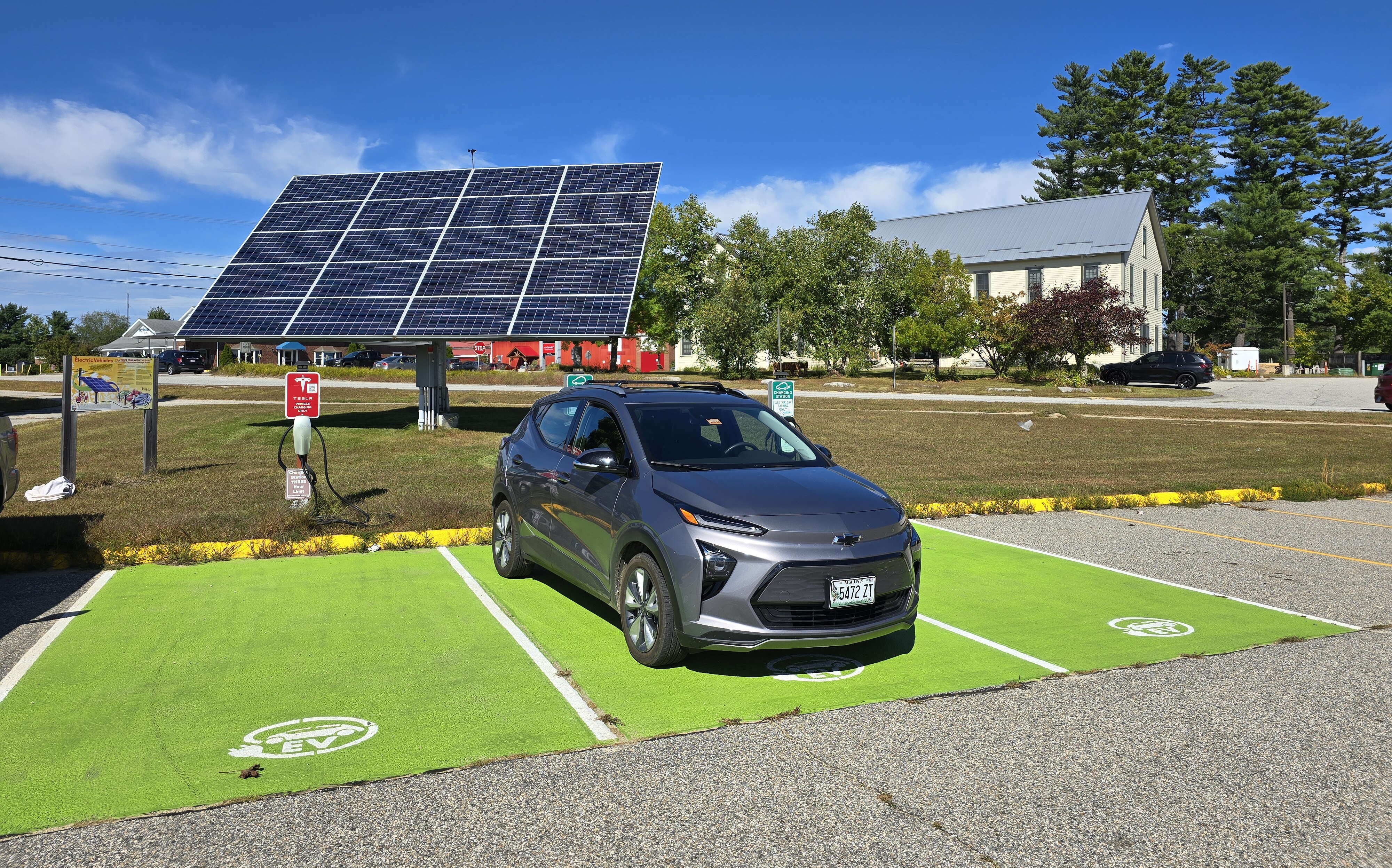 A car sits on a green mat near solar panels.