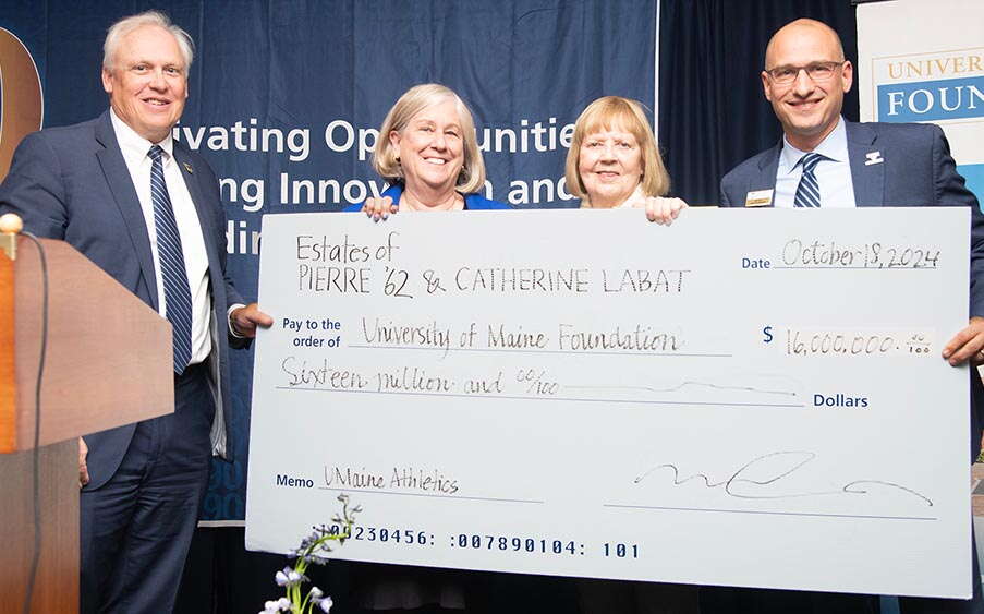 Four people pose with an oversize check.