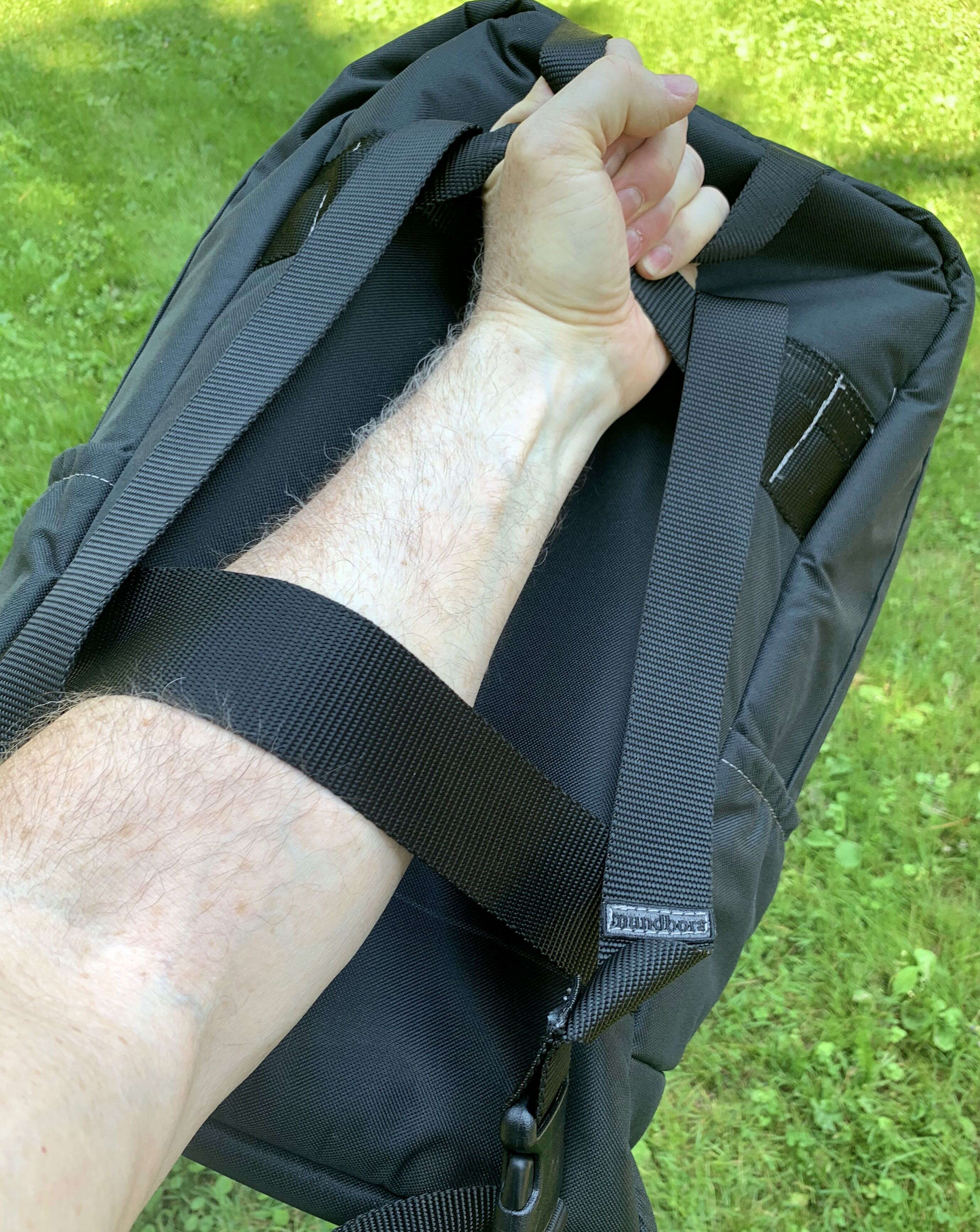 A hand is thrust through straps on a bag.