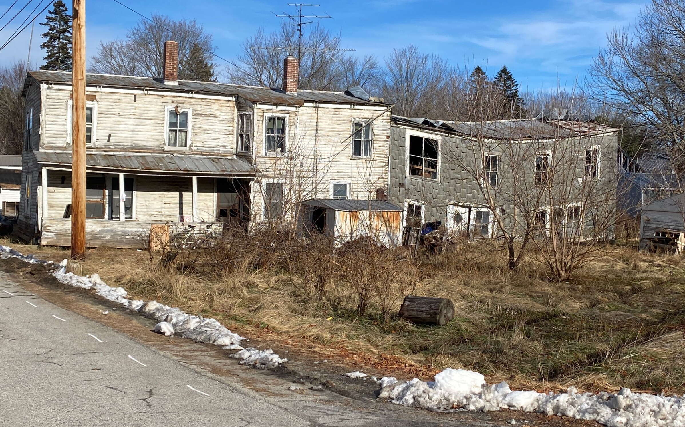 Dilapidated buildings and a weedy lawn.