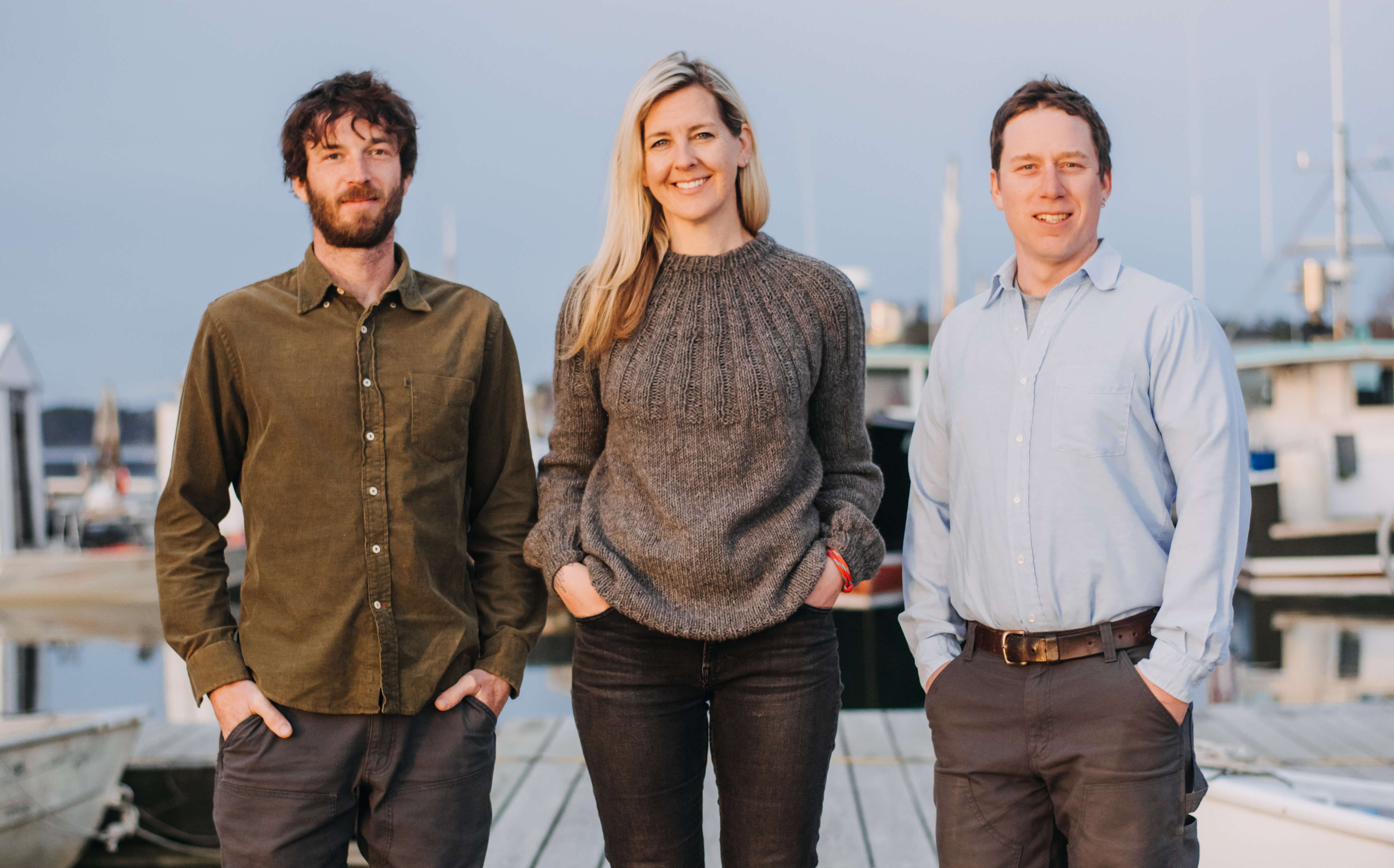 Three people pose on a dock.