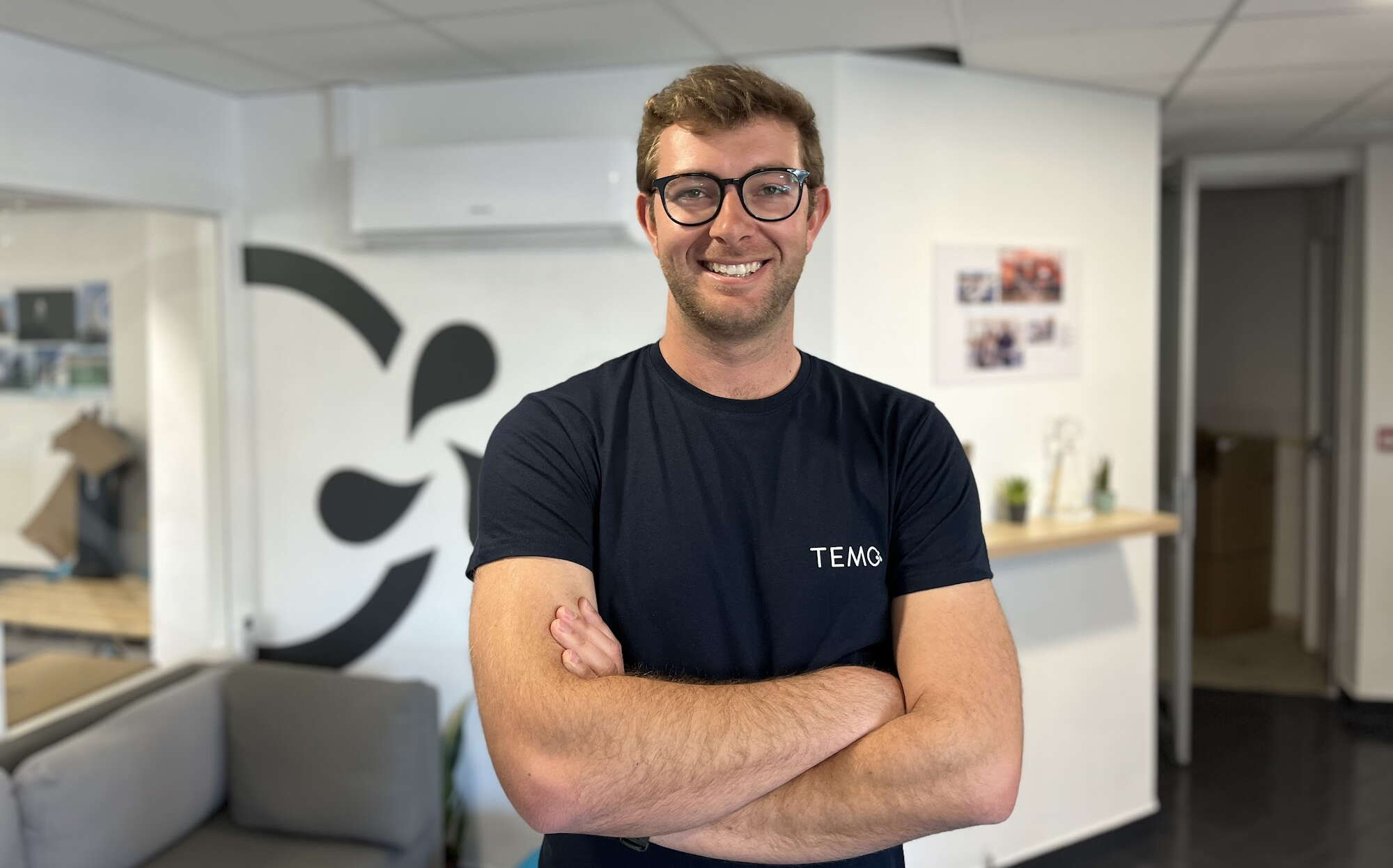 A person stands with his arms crossed in an office.