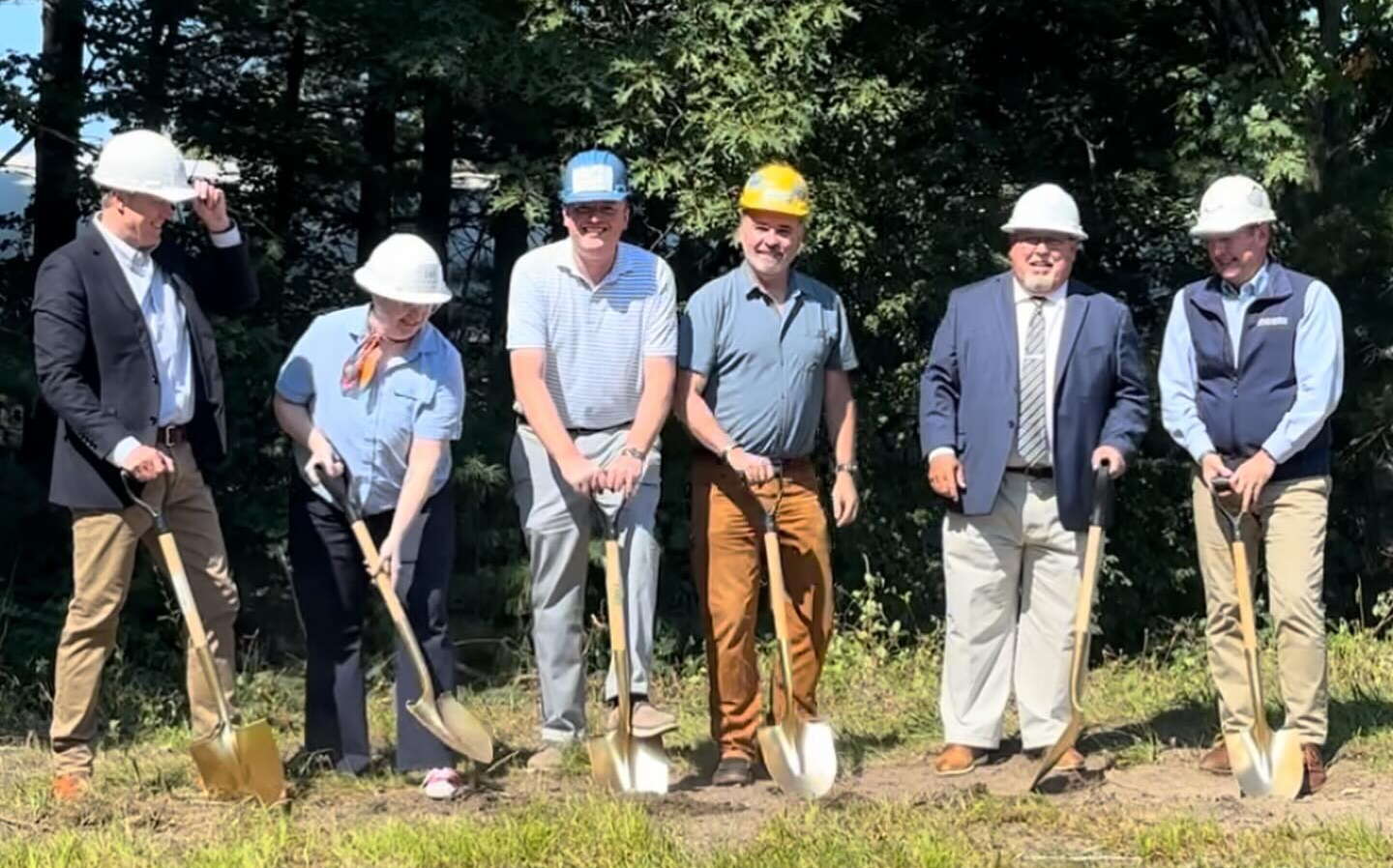 People pose in a line with shovels.