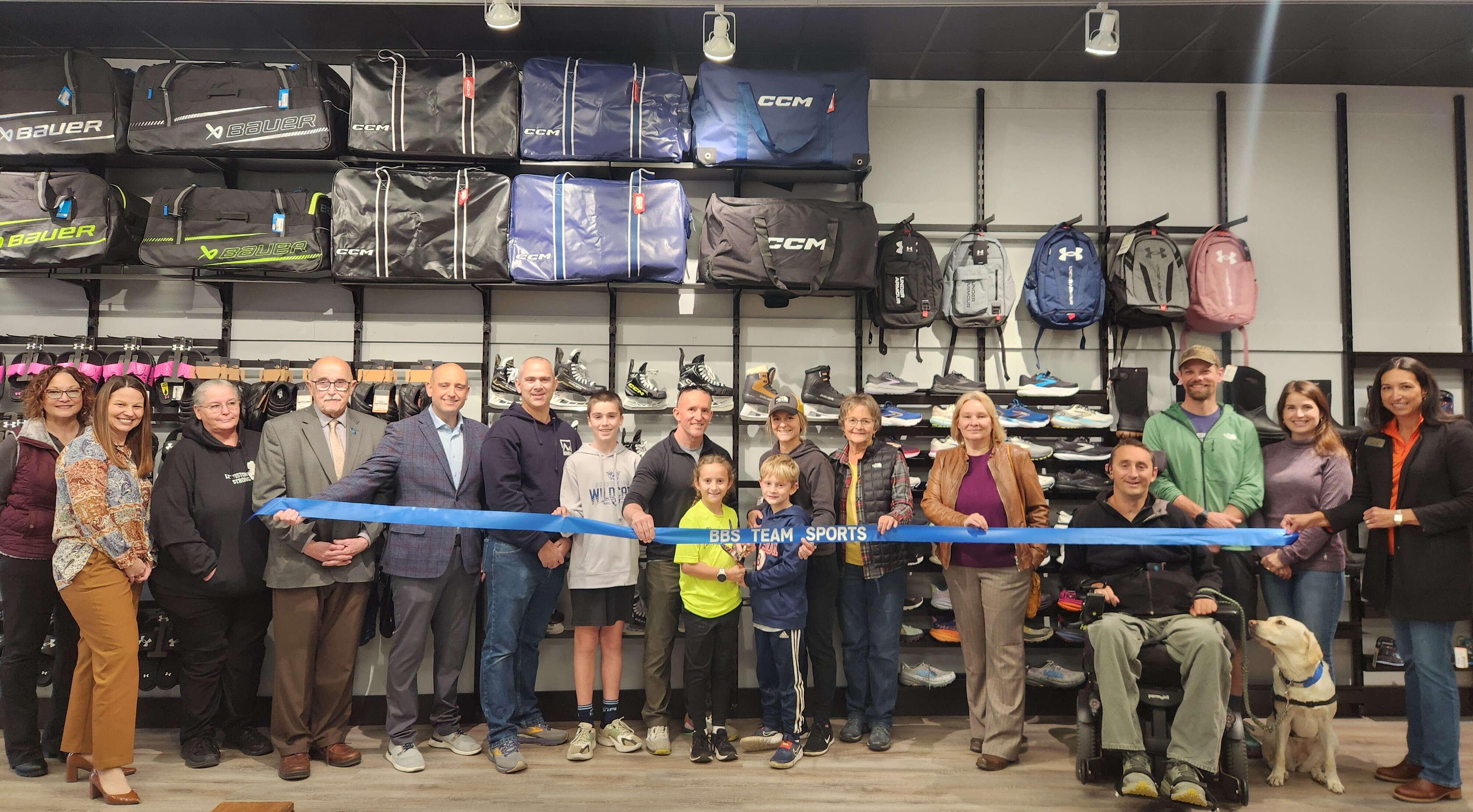 A group of people gather inside a building to cut a ribbon.