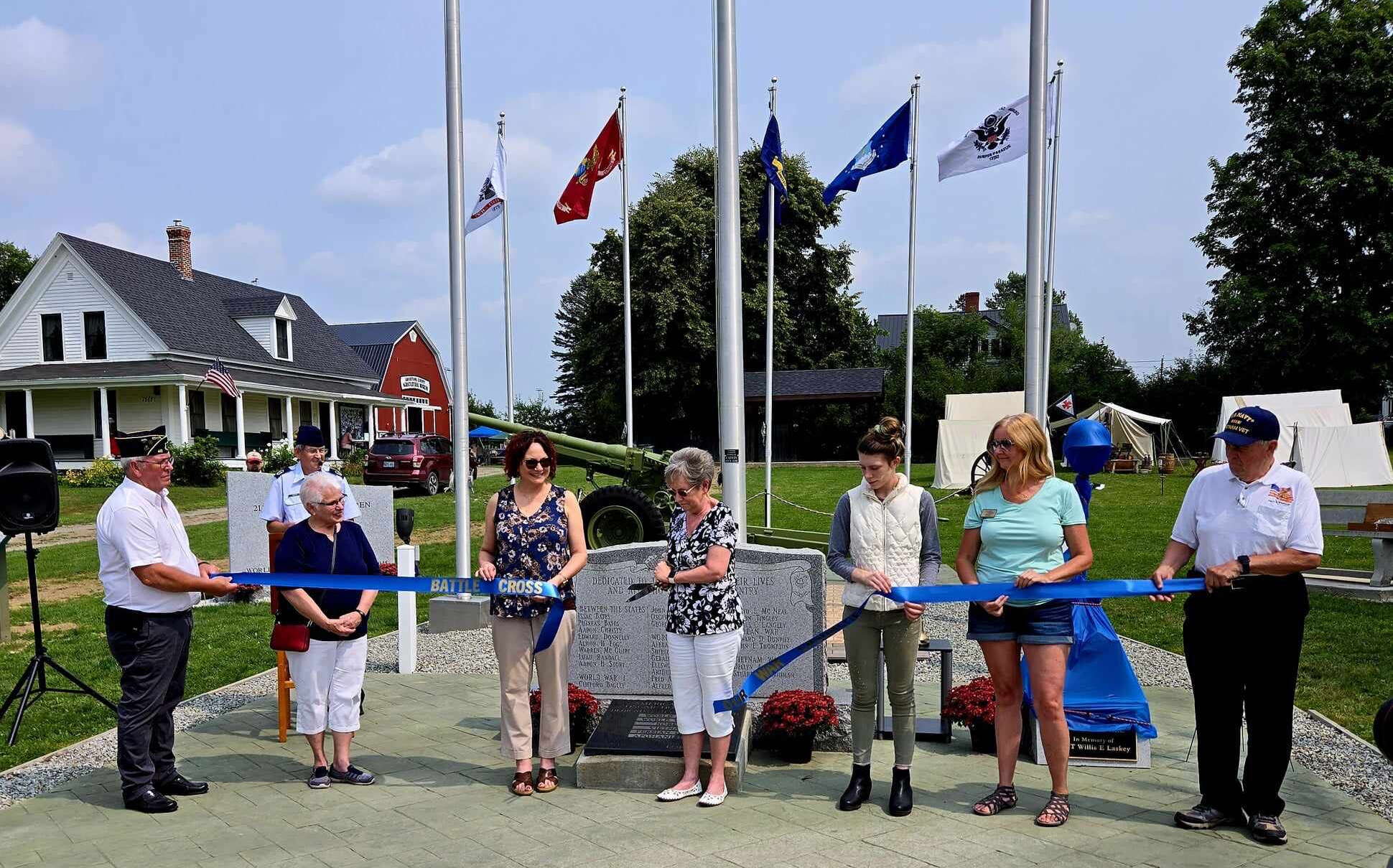 People gather at monument and cut a ribbon.