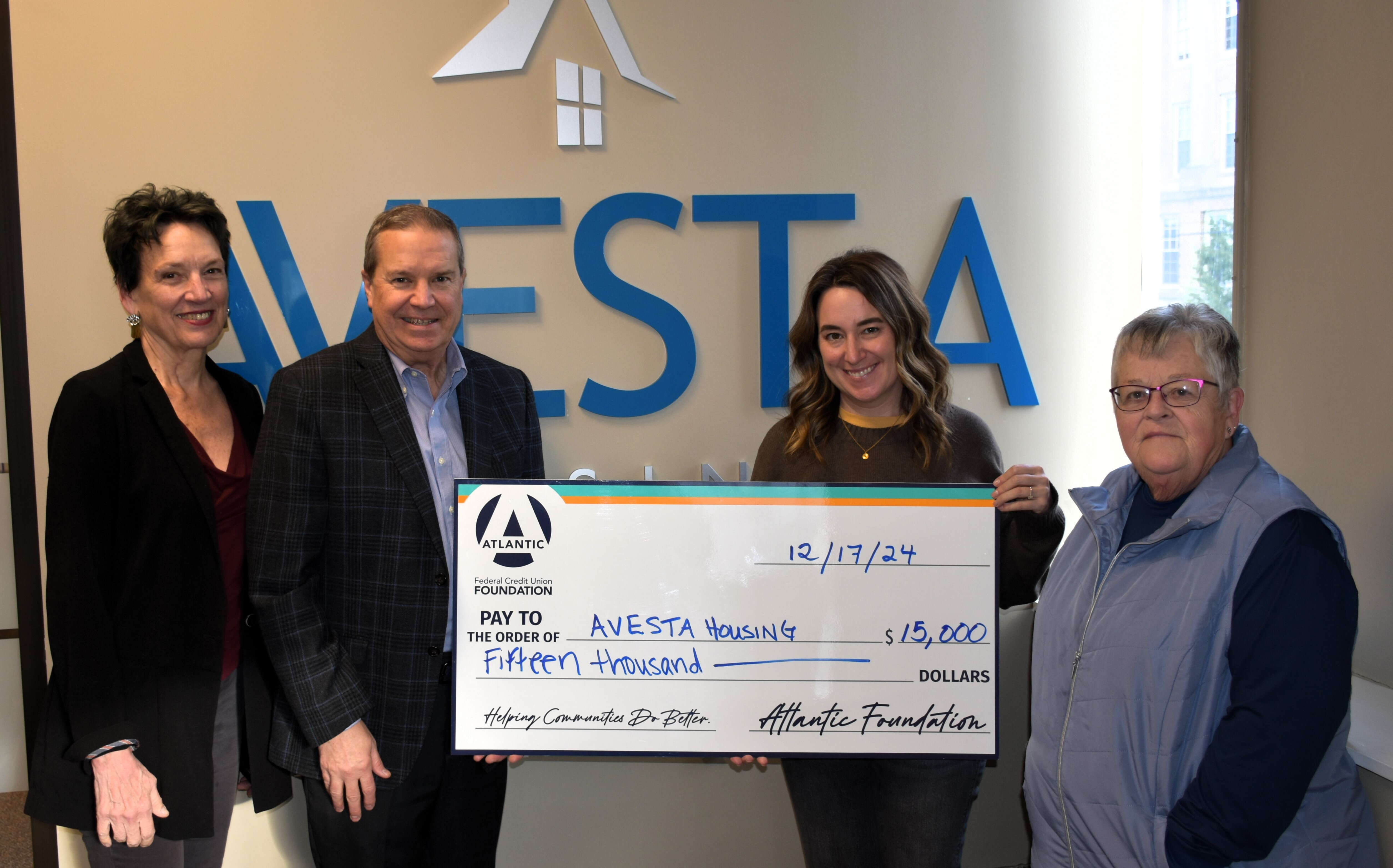 Four people hold an oversize check.