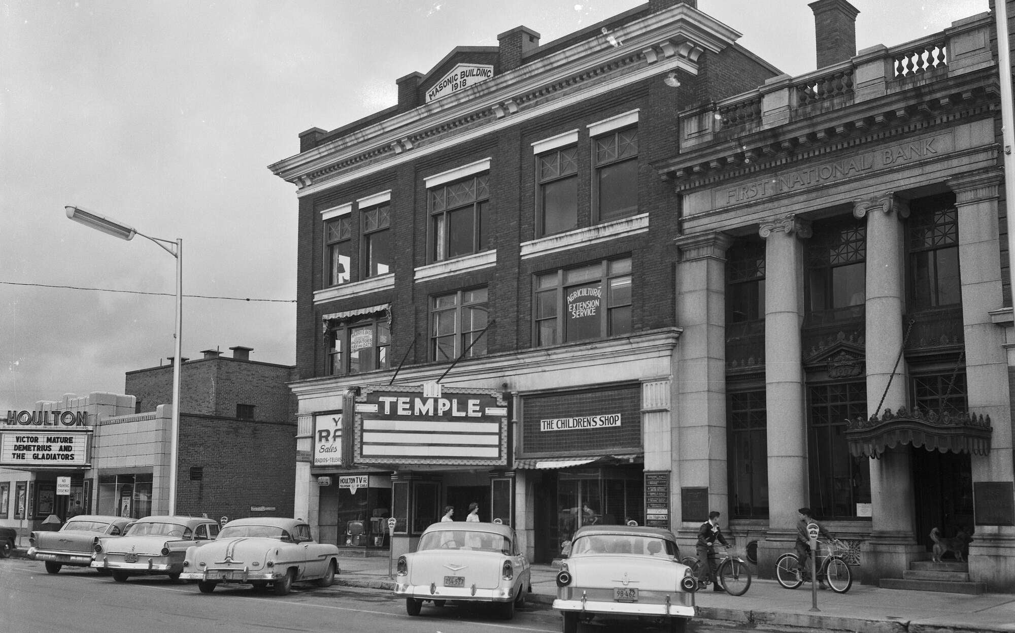 An old black-and-white photos shows old buildings and cars.