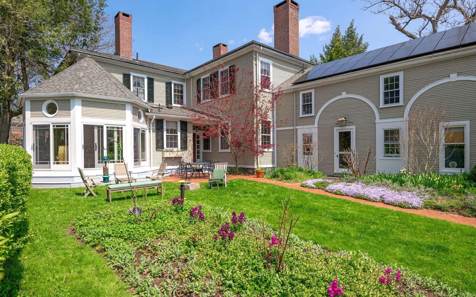 The rear of a house has lawns and gardens.