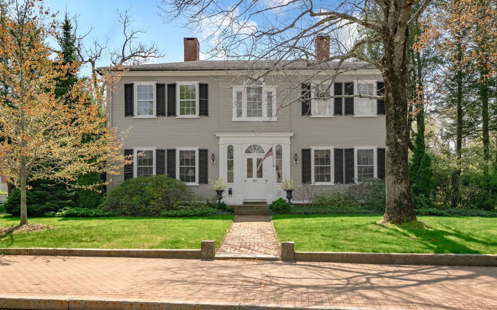 The exterior of a Colonial style house includes brick walks.