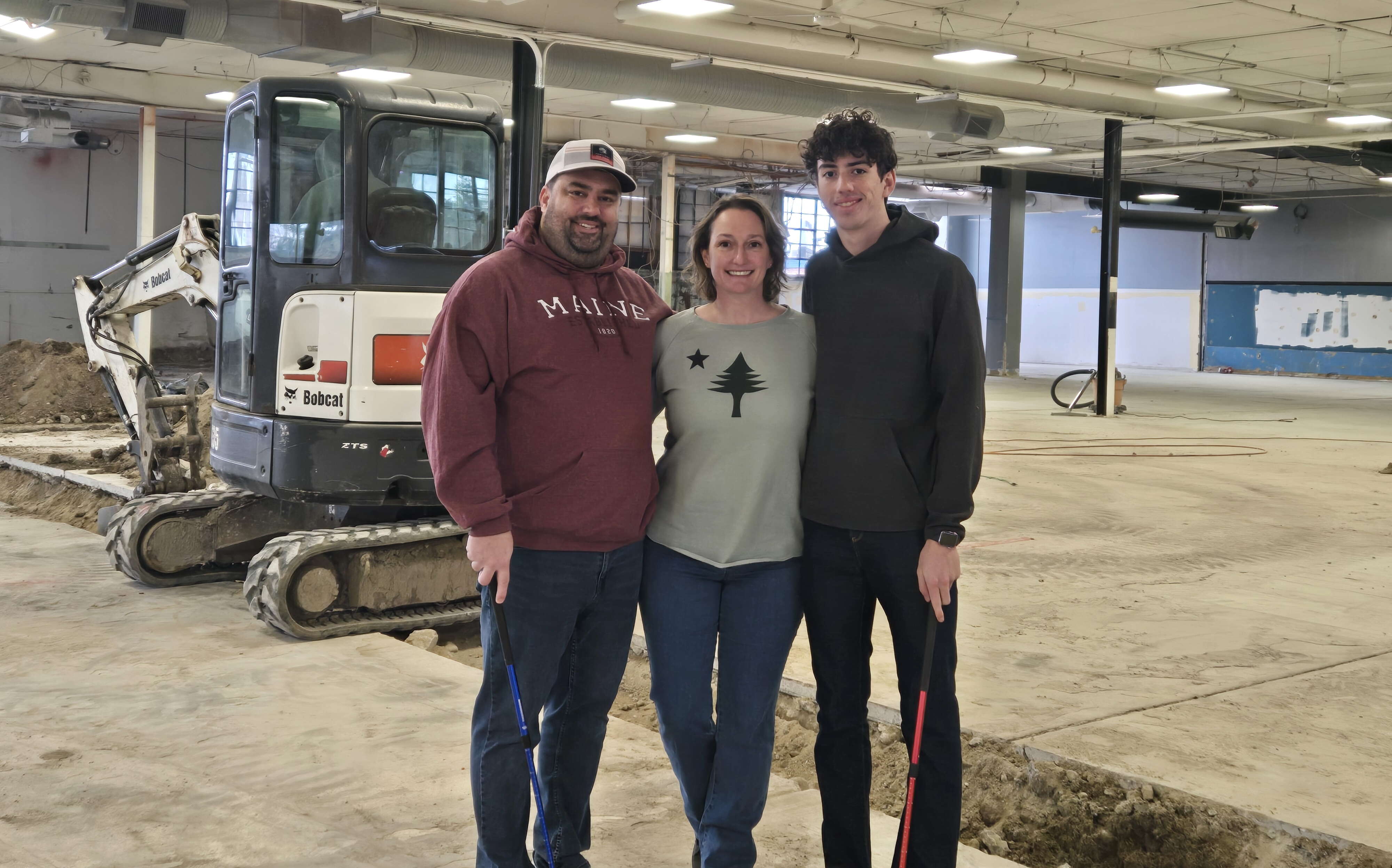 Three people standing inside a building where construction is underway.