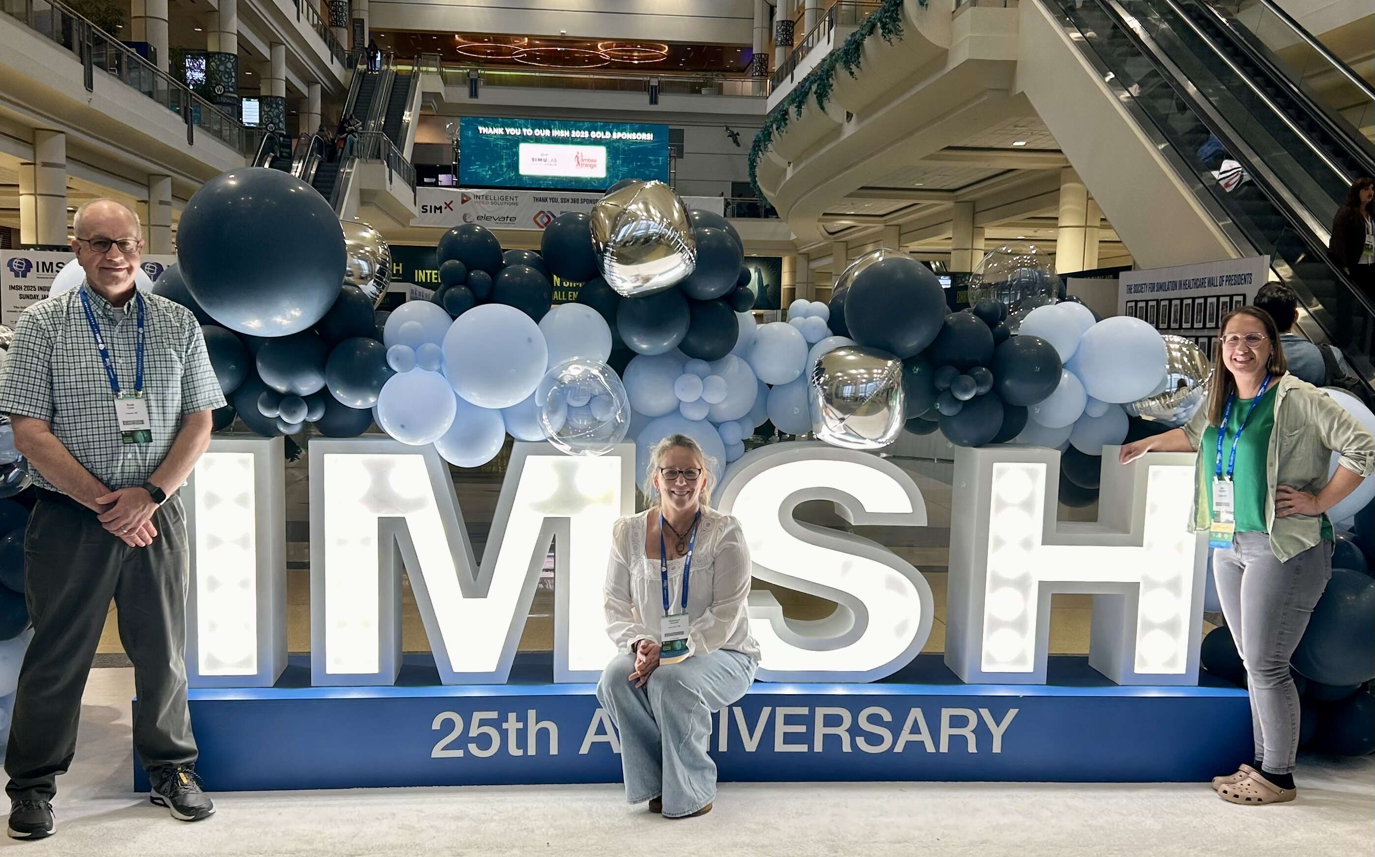 People pose with a lit sign and balloons.