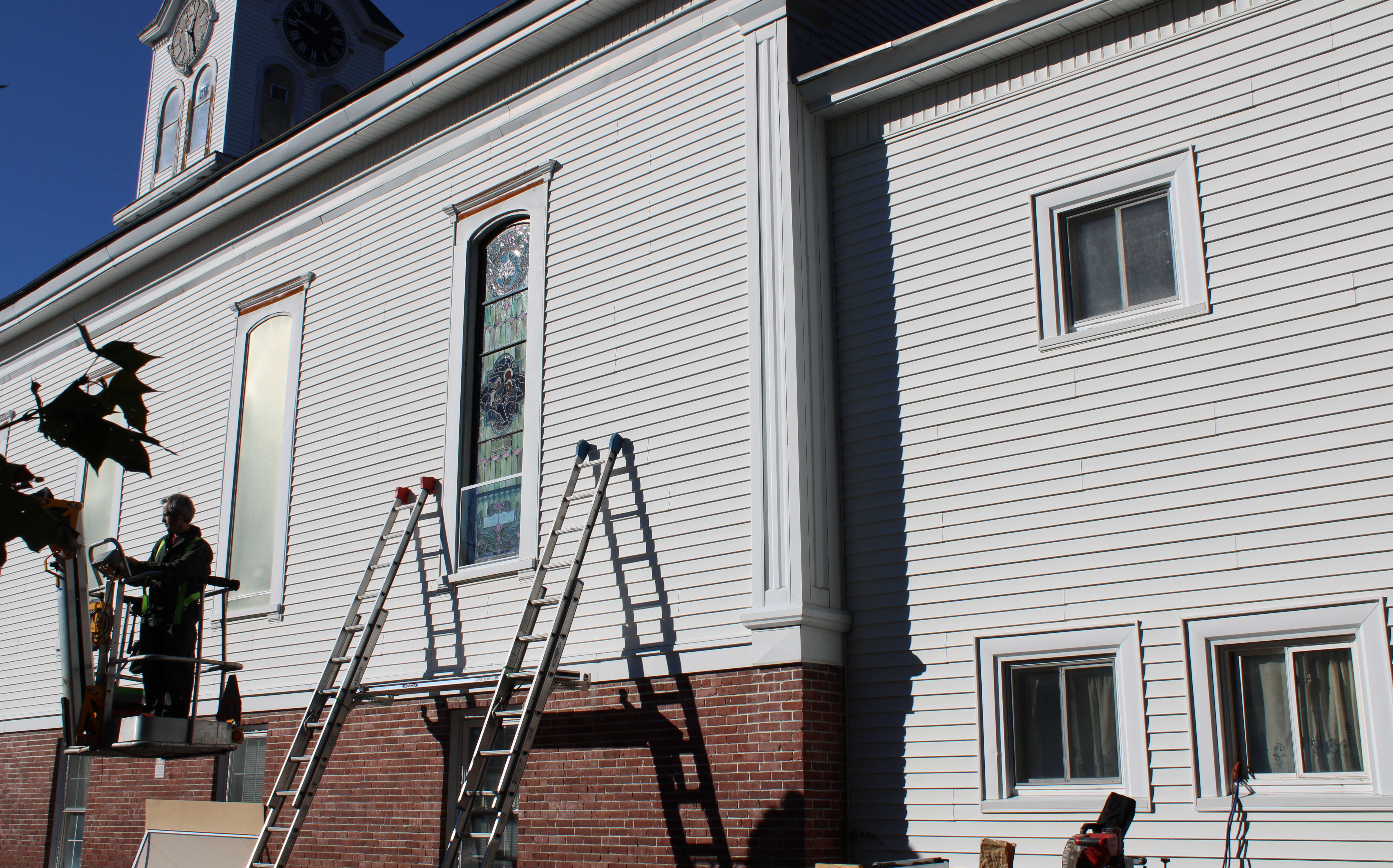 The exterior of a bulding has ladders leaning against it.