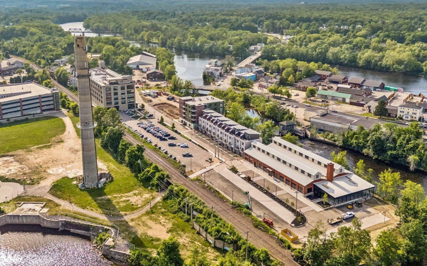 An aerial view shows buildings and a smokestack.