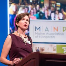 Jennifer Hutchins at a Maine Association of Nonprofits event (at a podium)