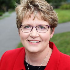 person in glasses and red blazer with necklace