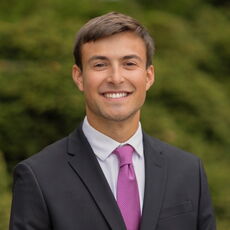 person in suit jacket and pink tie smiling