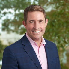 person smiling in pink buttondown and blue blazer