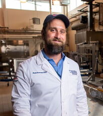 person in white coat, ballcap and beard