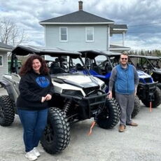 2 people standing with lineup of ATVs