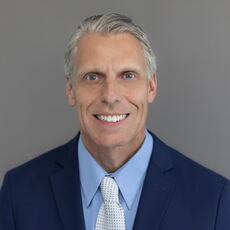 Man in a blue suit with a cream tie. 