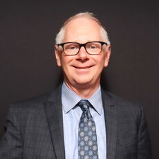 Man in a grey suit with a blue tie.