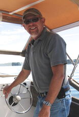 A person stands at a boat helm.