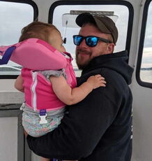 A person stands with a baby on a boat.