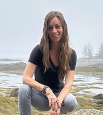 A person poses on a beach.