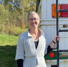 A person poses outside of a bus.