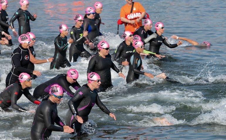Swimmers in wet suits and bathing caps entering the water in Tri for a Cure, in summer 2019.