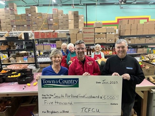 People in a food cupboard holding a check from Town & Country FCU