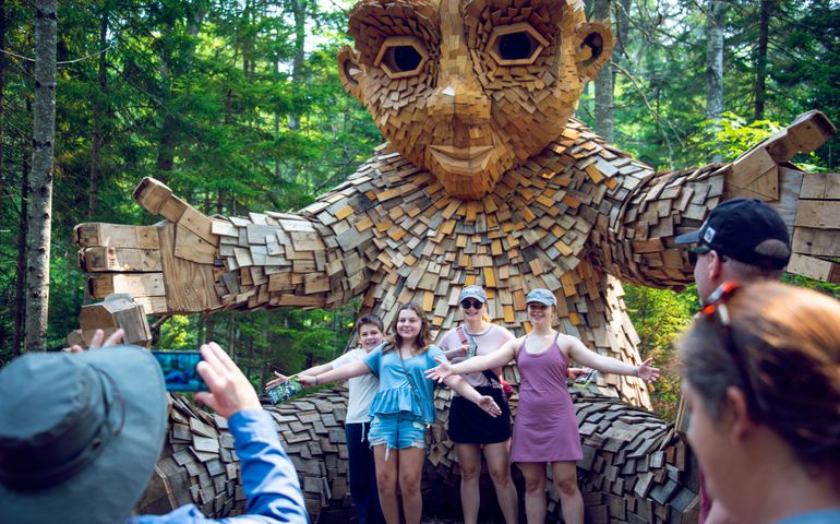 Four people having their photo taken with giant troll at Coastal Maine Botanical Gardens