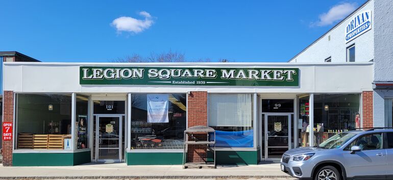 long storefront with sign and car