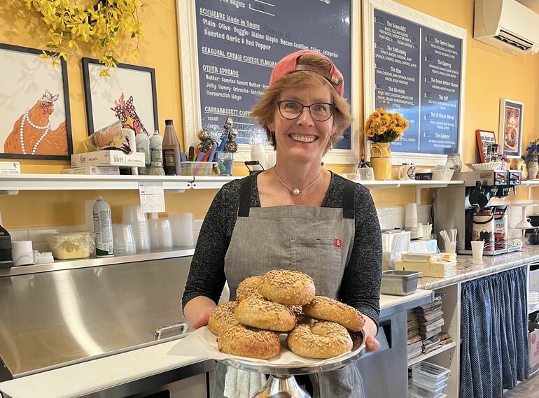 person smiling with tray of bagels